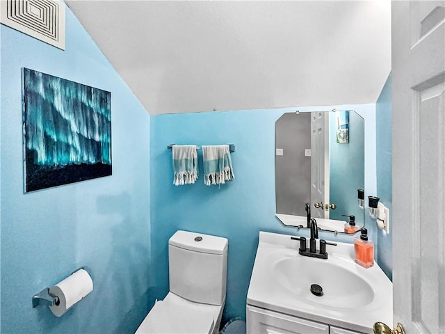 bathroom with vaulted ceiling, toilet, and vanity