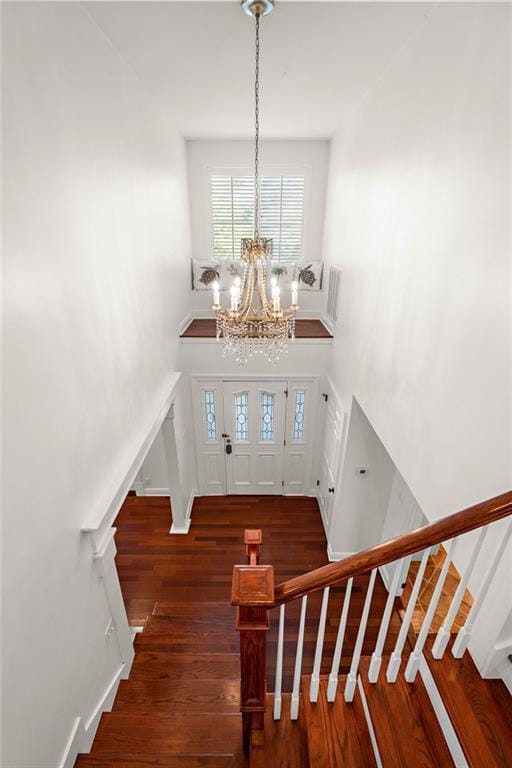 entrance foyer with dark hardwood / wood-style floors, a high ceiling, and a notable chandelier