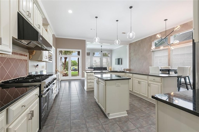 kitchen featuring pendant lighting, tasteful backsplash, a center island, dark tile flooring, and range with two ovens
