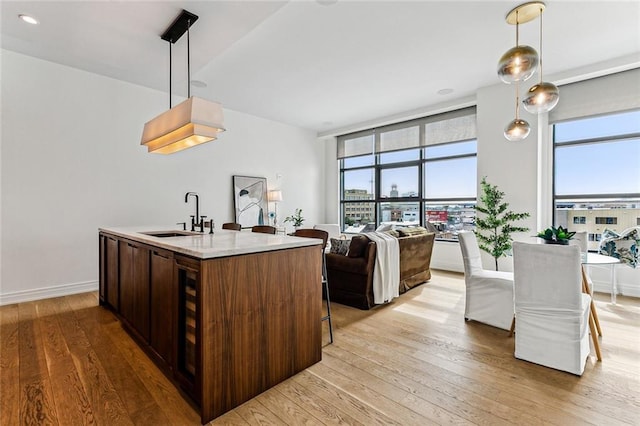 kitchen featuring sink, decorative light fixtures, light hardwood / wood-style floors, and light stone countertops