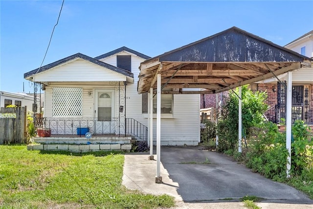 view of front of home featuring covered porch, a carport, and a front lawn