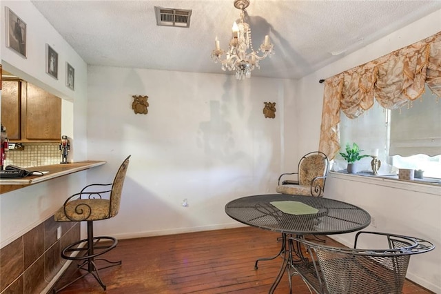 dining room with a textured ceiling, dark hardwood / wood-style flooring, and an inviting chandelier