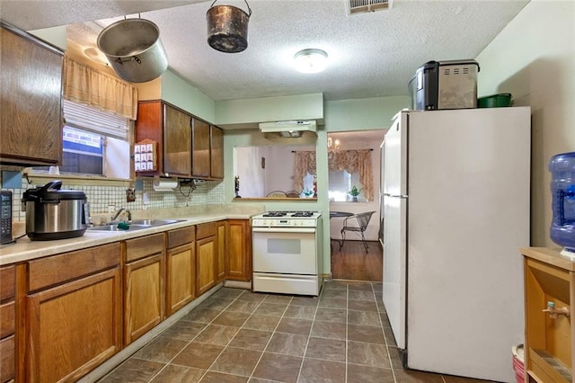 kitchen with a textured ceiling, sink, white appliances, backsplash, and dark hardwood / wood-style floors