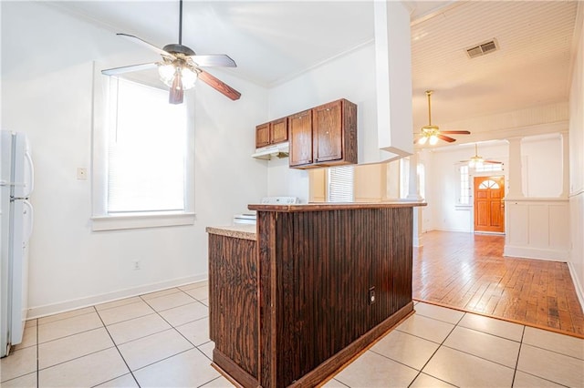 kitchen featuring kitchen peninsula, light hardwood / wood-style flooring, range, crown molding, and white fridge