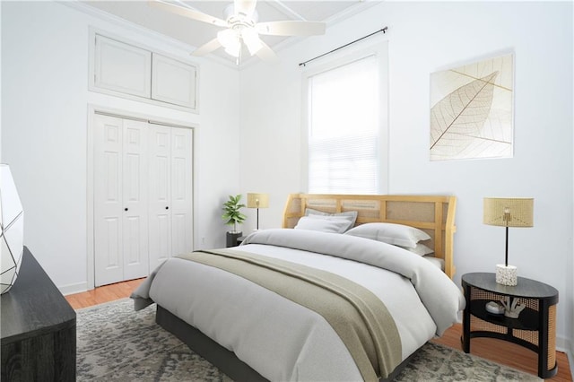 bedroom with ornamental molding, hardwood / wood-style flooring, a closet, and ceiling fan