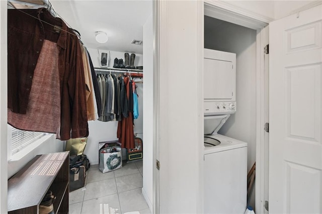 laundry area with stacked washer / dryer and light tile patterned flooring