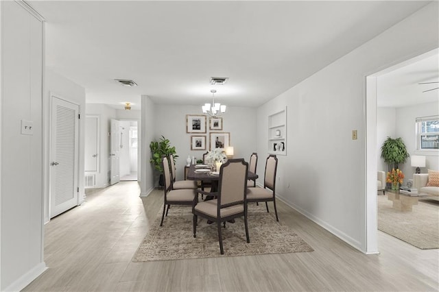 dining space with ceiling fan with notable chandelier and light hardwood / wood-style floors