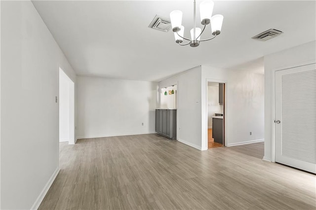 unfurnished living room with hardwood / wood-style floors and an inviting chandelier