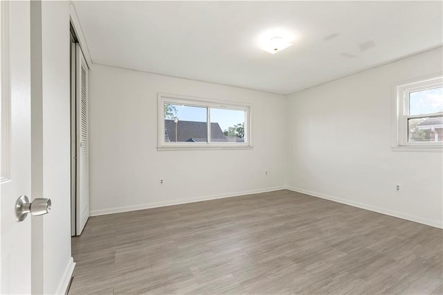 unfurnished bedroom with a closet, wood-type flooring, and multiple windows