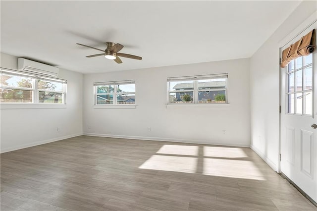 spare room with ceiling fan, a wall unit AC, and light hardwood / wood-style flooring