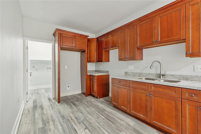 kitchen featuring light hardwood / wood-style floors, sink, and light stone countertops