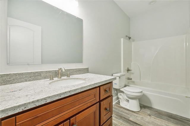 full bathroom featuring washtub / shower combination, vanity, hardwood / wood-style flooring, and toilet