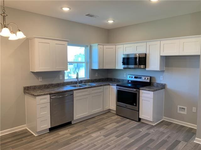 kitchen with sink, pendant lighting, stainless steel appliances, and white cabinetry