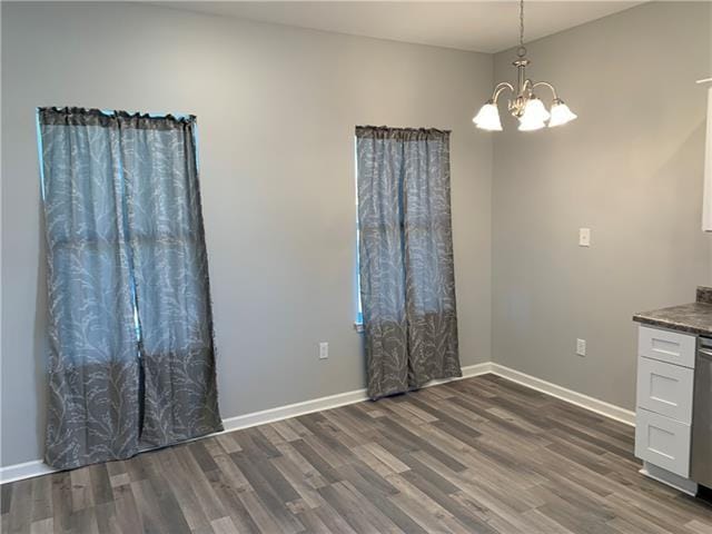 unfurnished dining area with dark hardwood / wood-style flooring and a notable chandelier