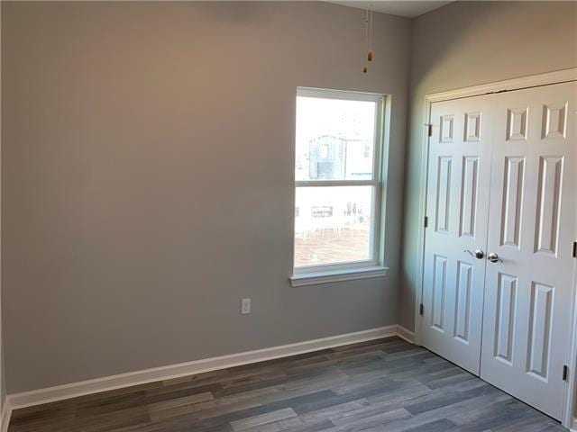 unfurnished bedroom featuring a closet, multiple windows, and dark wood-type flooring