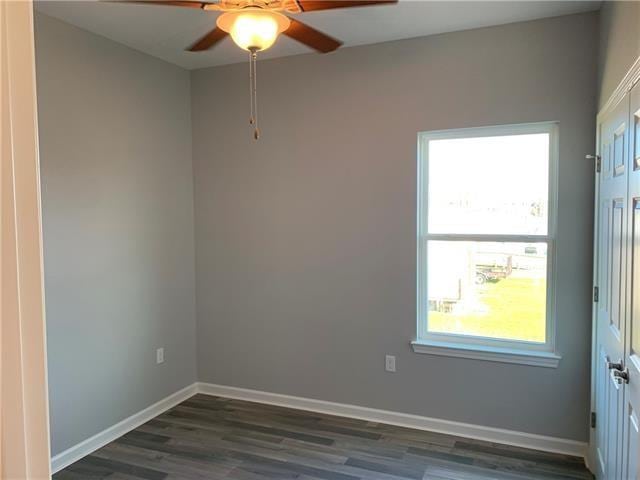 unfurnished room with ceiling fan and dark wood-type flooring