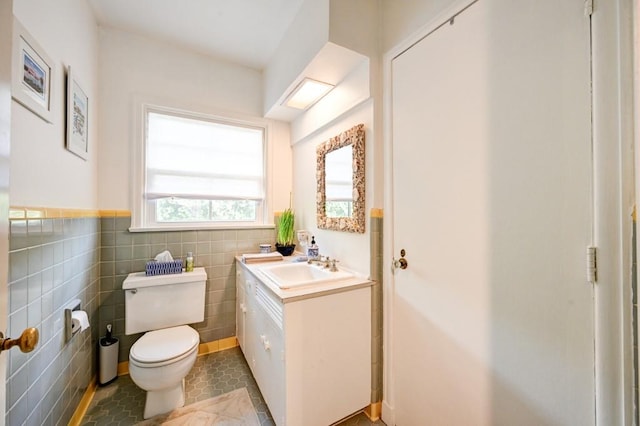 bathroom with tile walls, large vanity, toilet, and tile flooring