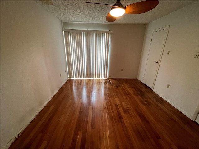 empty room featuring ceiling fan, dark wood-type flooring, and a textured ceiling