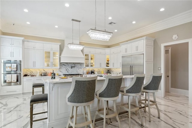 kitchen with backsplash, a spacious island, a kitchen bar, white cabinets, and appliances with stainless steel finishes