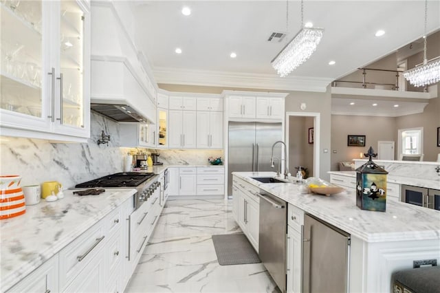 kitchen featuring stainless steel appliances, a spacious island, sink, white cabinetry, and hanging light fixtures