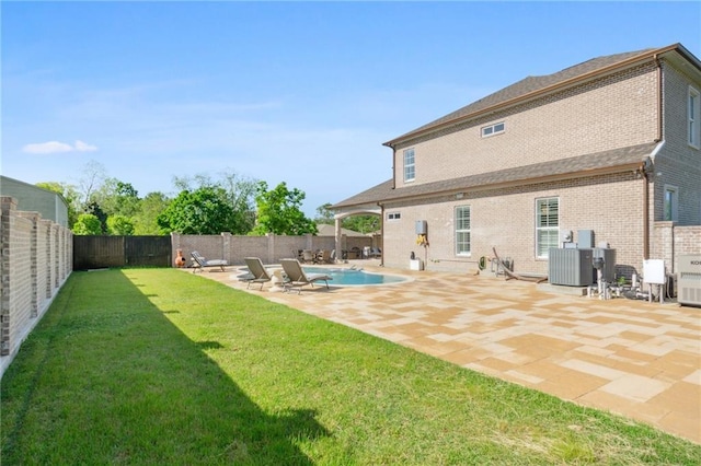 rear view of property featuring a fenced in pool, a yard, cooling unit, and a patio