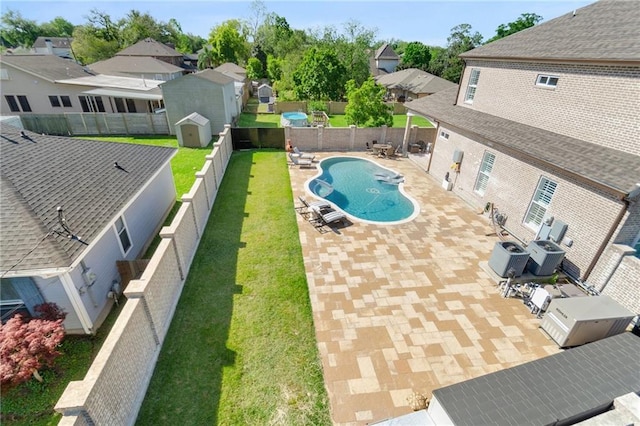 view of swimming pool featuring a lawn, a storage unit, cooling unit, and a patio area