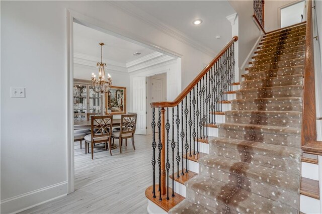 stairway featuring light hardwood / wood-style flooring, a notable chandelier, and ornamental molding