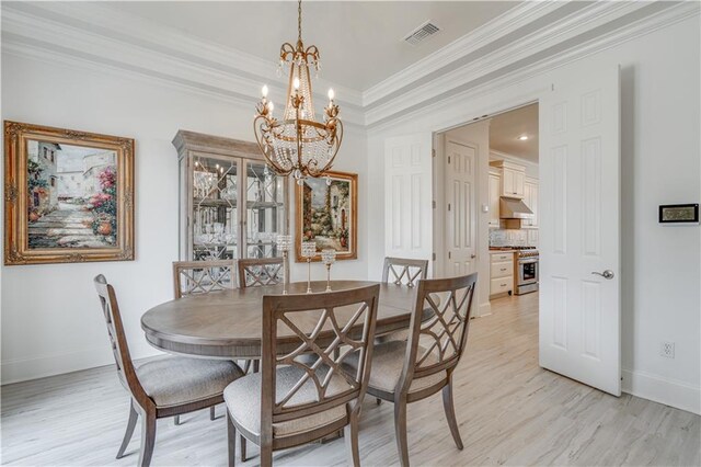 dining area featuring ornamental molding, an inviting chandelier, light hardwood / wood-style flooring, and a raised ceiling