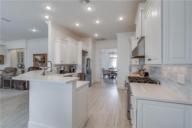 kitchen featuring appliances with stainless steel finishes, light hardwood / wood-style floors, backsplash, white cabinetry, and ornamental molding