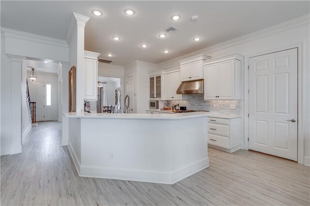 kitchen featuring white cabinets, backsplash, crown molding, and decorative columns