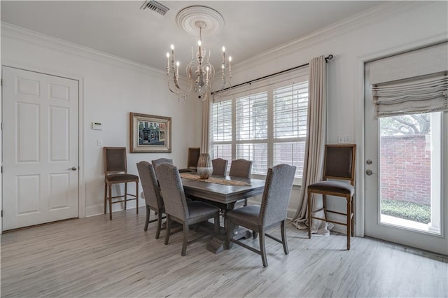 dining room featuring light hardwood / wood-style floors, an inviting chandelier, and crown molding