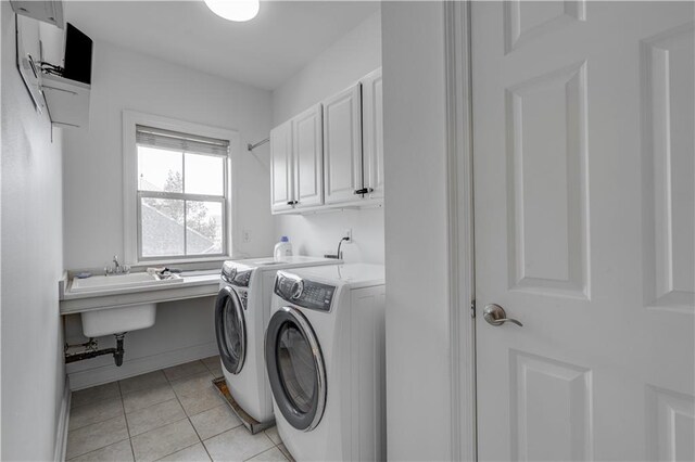 laundry area featuring washing machine and dryer, cabinets, sink, and light tile flooring