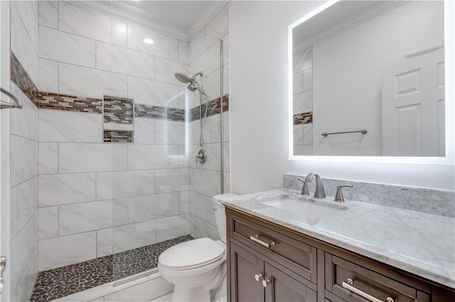 bathroom featuring vanity, crown molding, toilet, and a tile shower