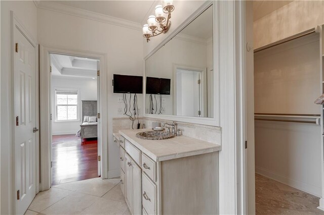 bathroom with vanity with extensive cabinet space, crown molding, tile flooring, a notable chandelier, and a raised ceiling