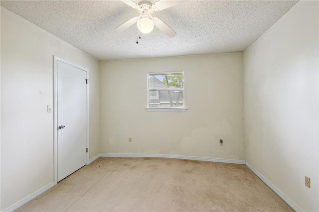 empty room with light colored carpet, ceiling fan, and a textured ceiling