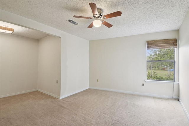 spare room featuring light carpet, ceiling fan, and a textured ceiling