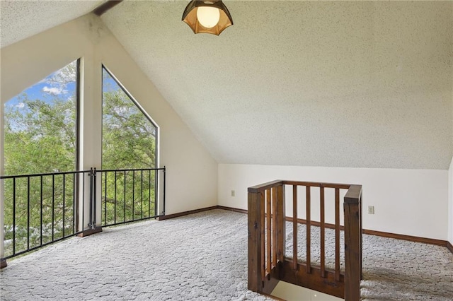 bonus room featuring lofted ceiling, carpet flooring, and a textured ceiling