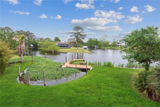 view of home's community with a boat dock, a water view, and a yard