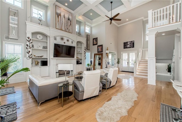 living room featuring a high ceiling, coffered ceiling, plenty of natural light, and light wood-type flooring