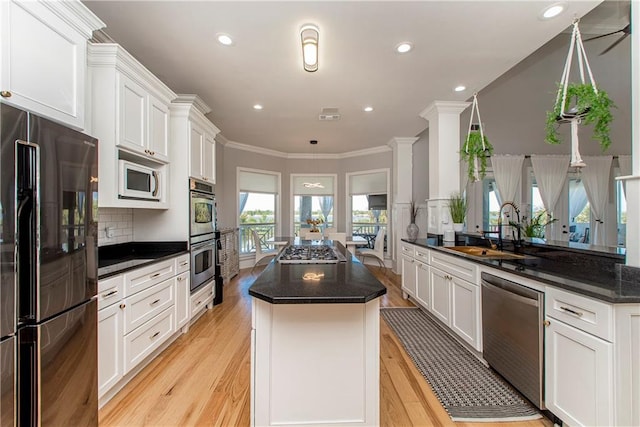 kitchen with crown molding, light hardwood / wood-style floors, appliances with stainless steel finishes, white cabinets, and sink