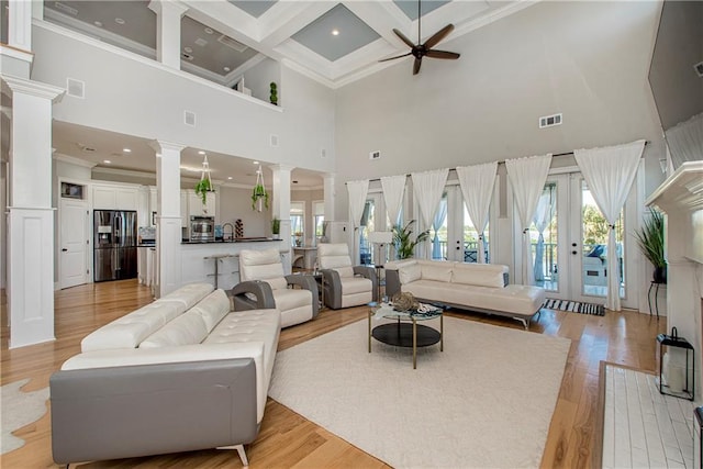 living room with beamed ceiling, a high ceiling, ornate columns, coffered ceiling, and ceiling fan