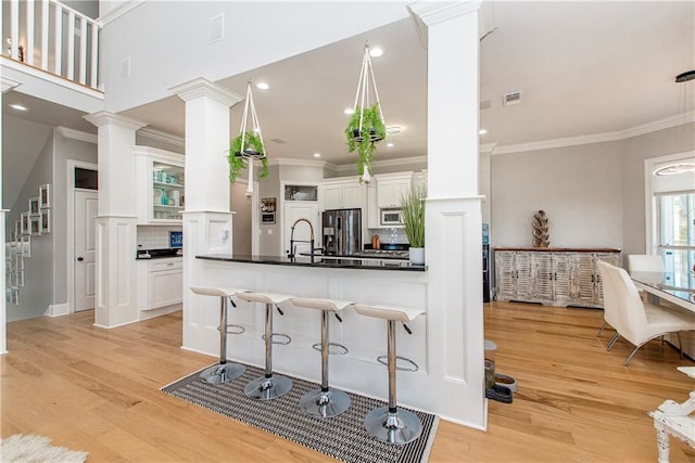 kitchen with backsplash, white cabinets, light hardwood / wood-style floors, and kitchen peninsula