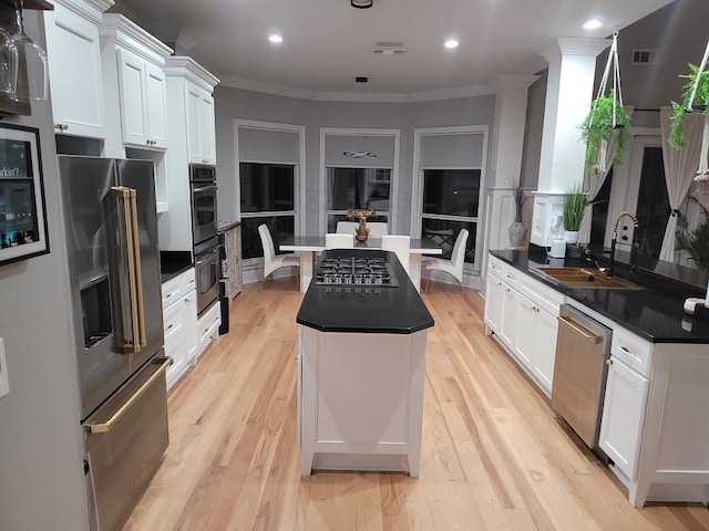 kitchen with a center island, stainless steel appliances, light hardwood / wood-style floors, and white cabinets