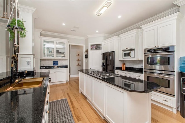 kitchen featuring a center island, stainless steel appliances, backsplash, and white cabinetry