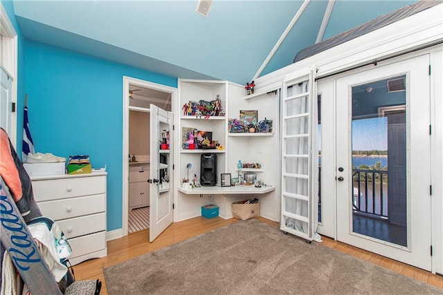 bedroom featuring access to outside, light hardwood / wood-style floors, french doors, and lofted ceiling