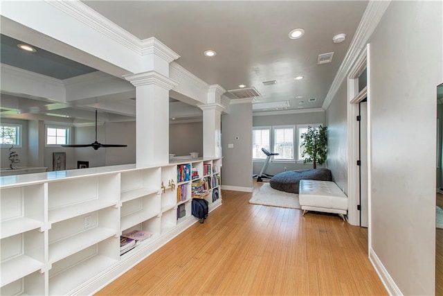 interior space featuring crown molding, light wood-type flooring, and ornate columns