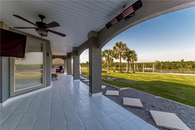 view of patio with ceiling fan and a water view