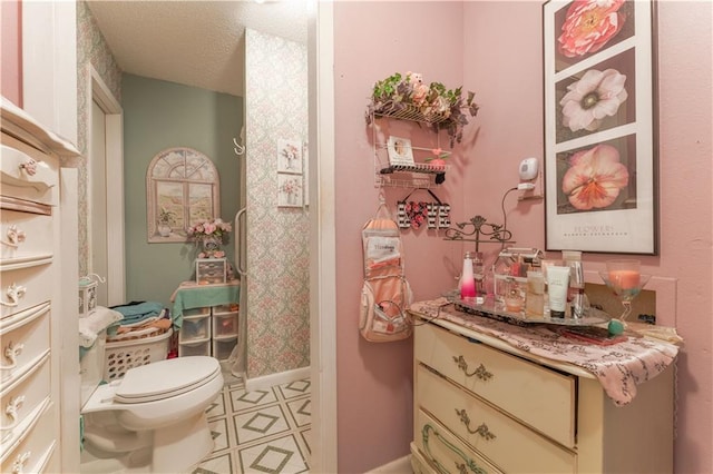 bathroom featuring tile flooring, vanity, toilet, and a textured ceiling