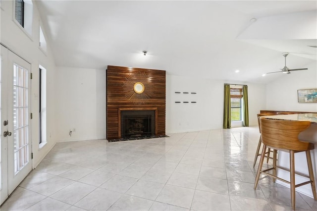 living room featuring french doors, lofted ceiling, light tile patterned floors, ceiling fan, and a fireplace