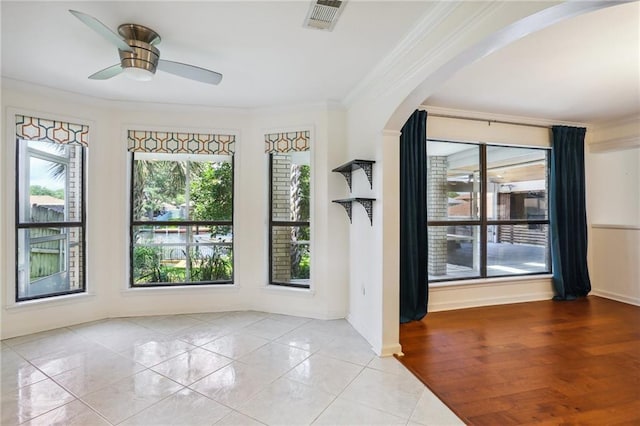 unfurnished room featuring crown molding, a wealth of natural light, ceiling fan, and light tile patterned flooring